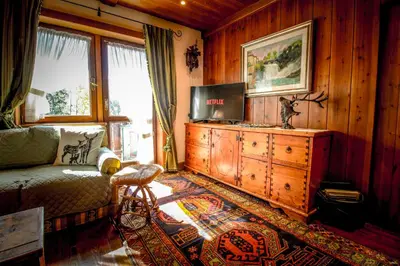 a living room with a couch and a tv on a dresser at Cortina Wood Home - a short walk from the center in Cortina dʼAmpezzo