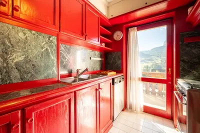 a kitchen with red cabinets and a sink and a window at Ca dei Castori in Cortina dʼAmpezzo