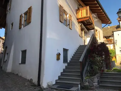 a white building with stairs and a balcony at Ca' Stella in Castello di Fiemme