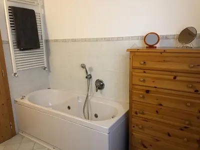 a bath tub in a bathroom with a wooden dresser at Ca' Stella in Castello di Fiemme