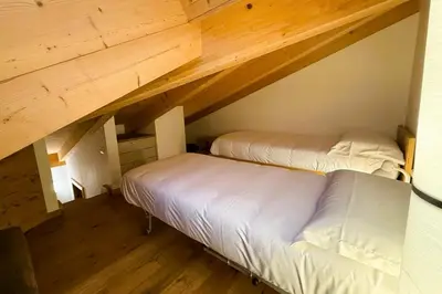 two beds in a attic room with wooden ceilings at Pragma Apartments - Wood Lodge Predazzo in Predazzo