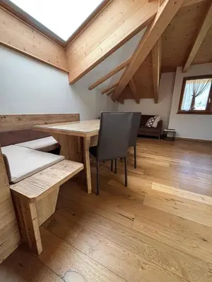 a room with a wooden table and a chair at Pragma Apartments - Wood Lodge Predazzo in Predazzo