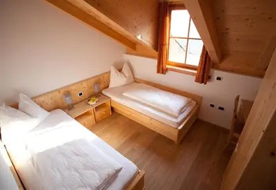 a small room with two beds and a window at Gasserhof Aicha in Naz-Sciaves