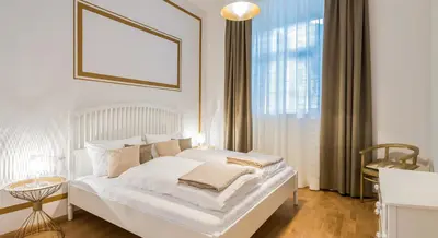 a white bed in a room with a large window at Park Residence Apartments in Bolzano