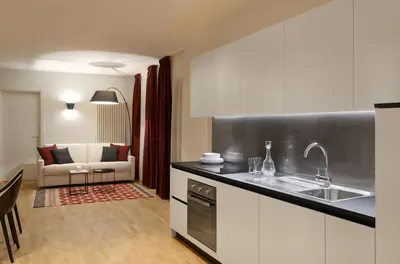 a kitchen with a sink and a living room at Park Residence Apartments in Bolzano