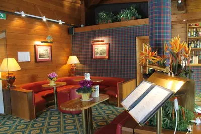 a waiting room with red couches and a piano at Hotel Majoni in Cortina dʼAmpezzo