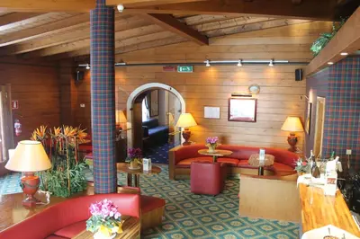 a hotel lobby with red couches and tables at Hotel Majoni in Cortina dʼAmpezzo