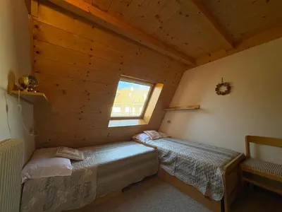 a bedroom with two beds in a wooden cabin at Mansarda Veronza in Castello di Fiemme