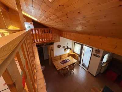 an overhead view of a wooden cabin with a table and a staircase at Mansarda Veronza in Castello di Fiemme