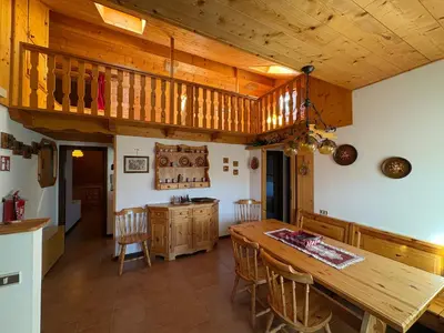 a kitchen with a wooden table and chairs at Mansarda Veronza in Castello di Fiemme