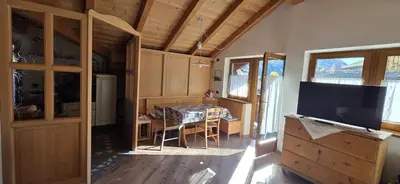 a living room with a television and a dining room table at Casa dal Cialie in Vigo di Fassa