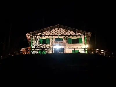 a house with lights on the side of it at night at Rifugio TEA Dolomiti in Falcade