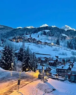 a town in the snow with mountains in the background at Rifugio TEA Dolomiti in Falcade