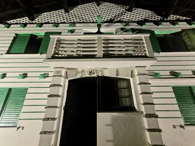 a white building with a black door and green windows at Rifugio TEA Dolomiti in Falcade