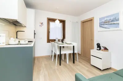 a kitchen and dining room with a table and chairs at Larice&Ribes Apartments in San Vito di Cadore