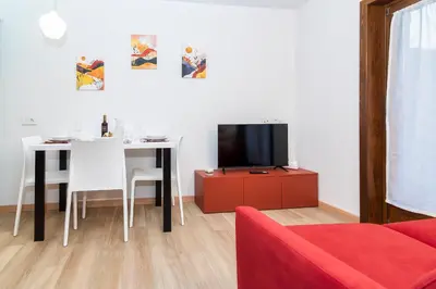 a living room with a tv and a table with chairs at Larice&Ribes Apartments in San Vito di Cadore