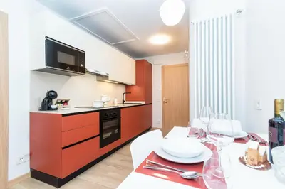 a kitchen with a table and a red cabinet at Larice&Ribes Apartments in San Vito di Cadore