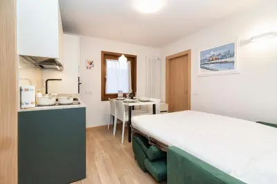 a small room with a bed and a kitchen at Larice&Ribes Apartments in San Vito di Cadore