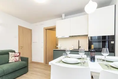 a kitchen and living room with a table with wine glasses at Larice&Ribes Apartments in San Vito di Cadore