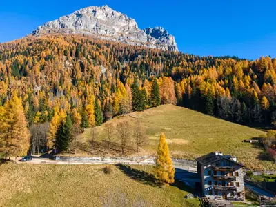 a building on a hill with a mountain in the background at Dreamful Cottage in Selva di Cadore
