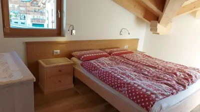 a bedroom with a bed with red sheets and a window at Mansarda Dolores in Canazei