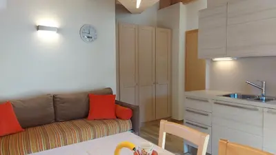 a living room with a couch and a kitchen at Mansarda Dolores in Canazei