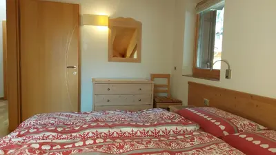 a bedroom with a bed and a dresser and a window at Mansarda Dolores in Canazei