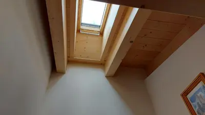 a room with a wooden ceiling and a window at Mansarda Dolores in Canazei