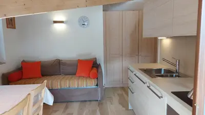 a kitchen with a couch with orange pillows on it at Mansarda Dolores in Canazei