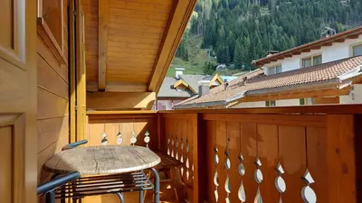 a wooden balcony with a table and chairs on it at Mansarda Dolores in Canazei