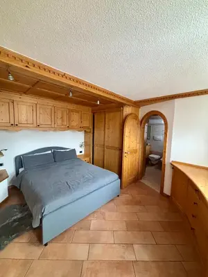 a bedroom with a bed and wooden cabinets at Pragma Apartments - Dolomiti by Valentina in Moena