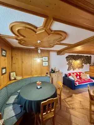 a living room with a table and a bed at Pragma Apartments - Dolomiti by Valentina in Moena