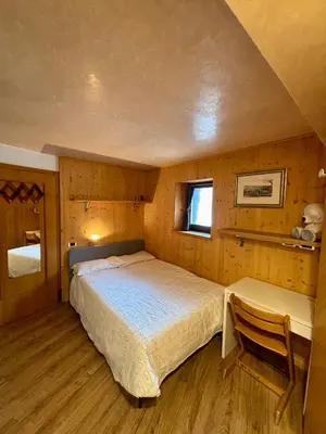 a bedroom with a bed and a chair in it at Pragma Apartments - Dolomiti by Valentina in Moena