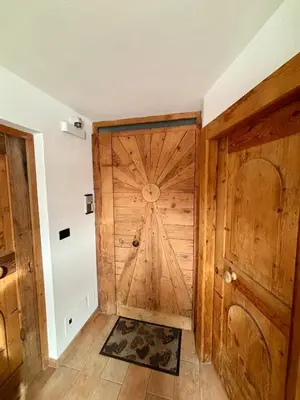 a large wooden door in a room with a tile floor at Pragma Apartments - Dolomiti by Valentina in Moena