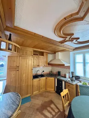 a large kitchen with wooden cabinets and a table at Pragma Apartments - Dolomiti by Valentina in Moena