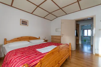 a bedroom with a large bed with a red blanket at Casa Iris in Falcade