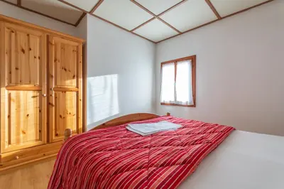 a bedroom with a bed with a red blanket at Casa Iris in Falcade