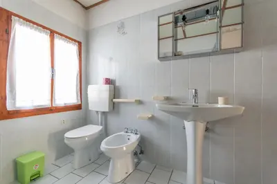 a white bathroom with a toilet and a sink at Casa Iris in Falcade