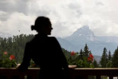 a woman looking out a window at a mountain at Bio Alpine Hotel Gran Fodà in San Vigilio Di Marebbe