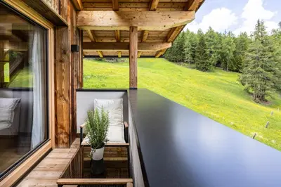 a bedroom with a large white bed and wooden walls at Bio Alpine Hotel Gran Fodà in San Vigilio Di Marebbe