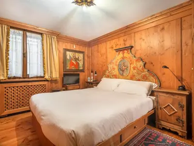 a bedroom with a bed with a wooden wall at Angiolina Charming Apartment R&R in Cortina dʼAmpezzo