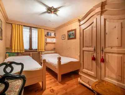 a bedroom with two beds and a ceiling fan at Angiolina Charming Apartment R&R in Cortina dʼAmpezzo