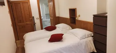 two beds with red pillows in a room at Bella Cortina - comodo al centro e impianti, con garage in Cortina dʼAmpezzo