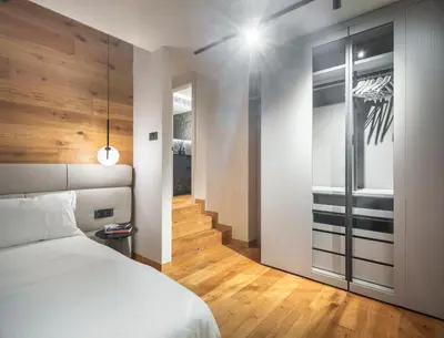 a bedroom with a white bed and a staircase at Cademai Alpenglow Chalet with Sauna R&R in Cortina dʼAmpezzo