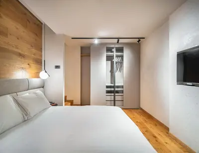 a bedroom with a white bed and a flat screen tv at Cademai Alpenglow Chalet with Sauna R&R in Cortina dʼAmpezzo