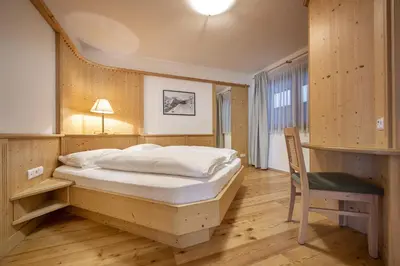 a bedroom with a bed and a desk and a chair at Marienstern Apartments in Santa Cristina in Val Gardena