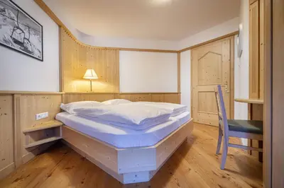 a bedroom with a bed and a table and a chair at Marienstern Apartments in Santa Cristina in Val Gardena