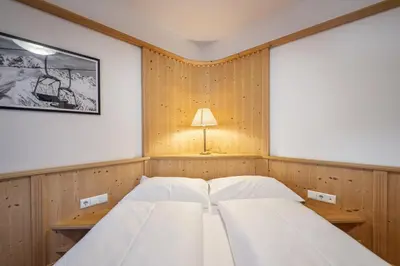 a bedroom with two beds and a lamp on the wall at Marienstern Apartments in Santa Cristina in Val Gardena