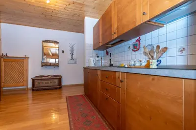 a kitchen with wooden cabinets and a red rug at Casa Paola in Rocca Pietore