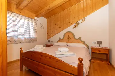 a bedroom with a wooden bed with towels on it at Casa Paola in Rocca Pietore